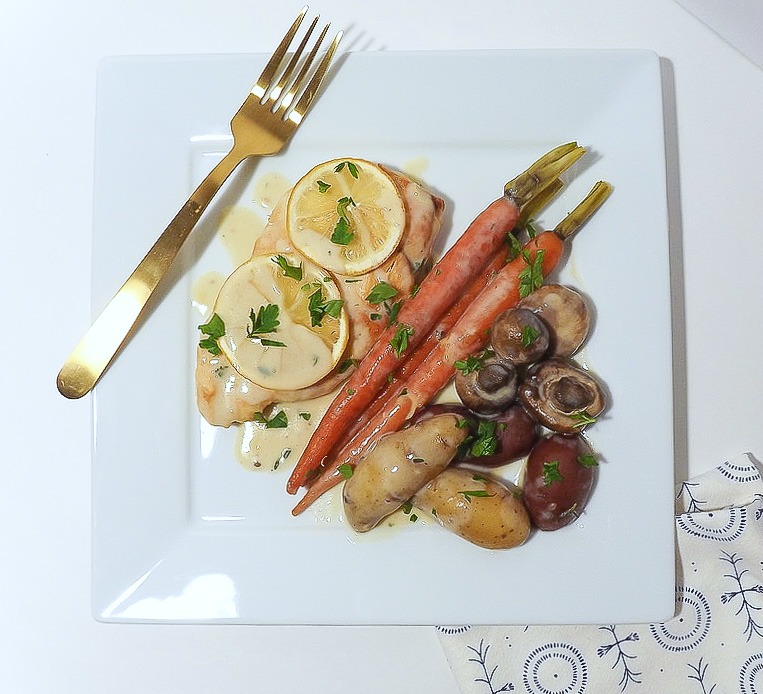 Roast chicken and veggies on a white plate with gold fork