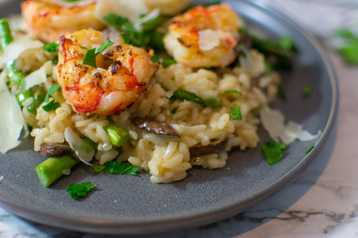 Closeup of risotto on a plate with shrimp and asparagus and mushrooms