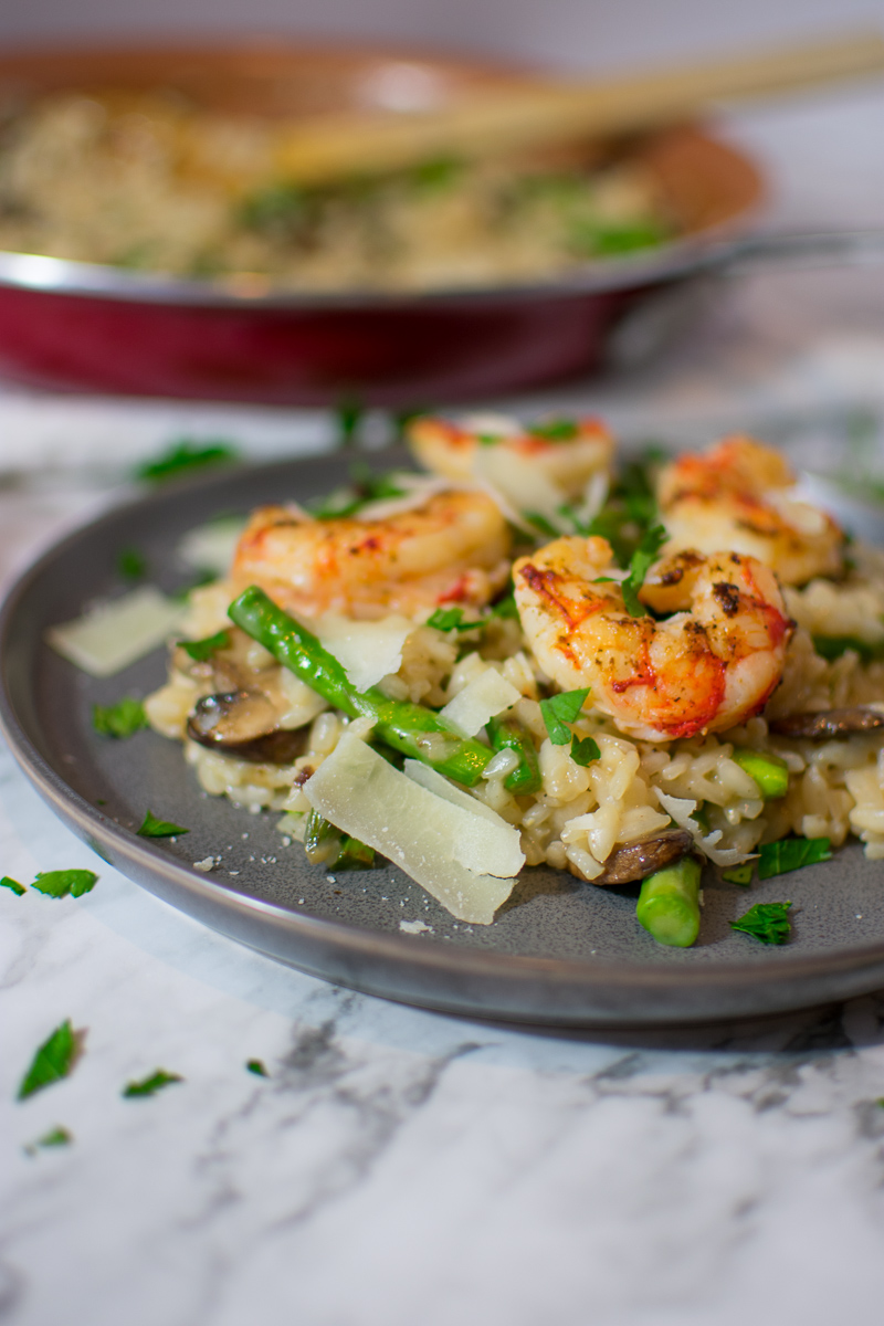 Closeup of risotto on a plate topped with shrimp and parmesan cheese