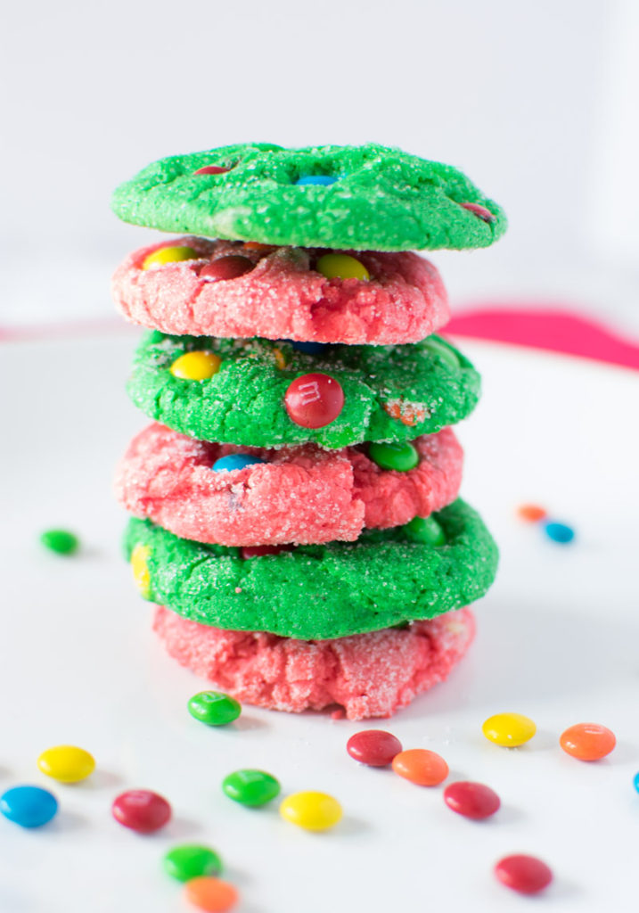 6 M&M Crinkle Christmas Cookies stacked on a plate with M&Ms sprinkled around