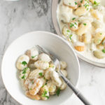 Overhead picture of Gnocchi with Gorgonzola Cream sauce in a small serving bowl with the corner of a large serving bowl