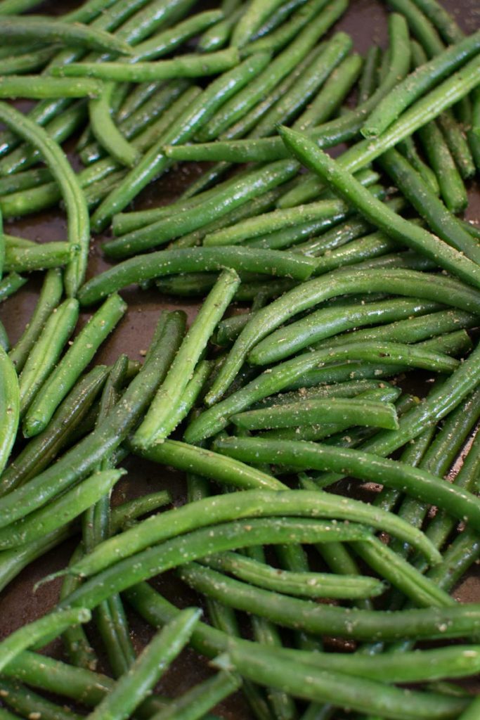 Close up picture of uncooked, seasoned beans on a baking sheet