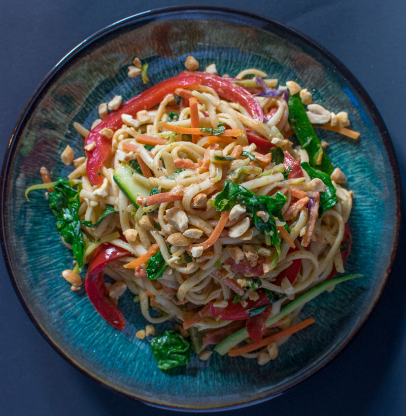 Overhead view of Spicy Almond Butter Vegetarian Noodles on a plate with a dark background
