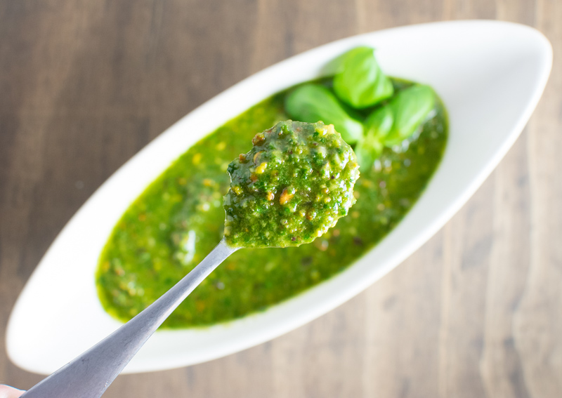 Close up of Vegan Pistachio Pesto in a spoon with large bowl of pesto in background