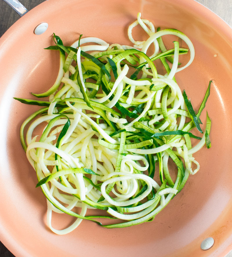Fresh zucchini noodles in a skillet