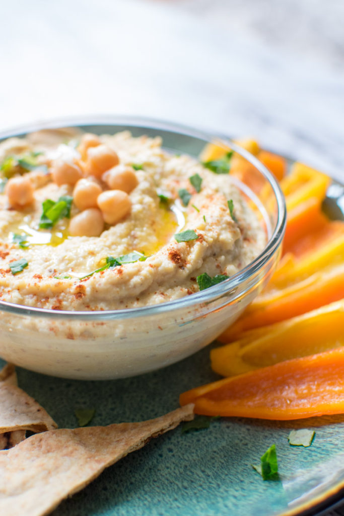 Hummus in bowl with veggies on a large plate