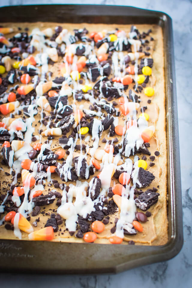 Cream cheese frosting drizzled on top of Halloween Sugar Cookie Pizza