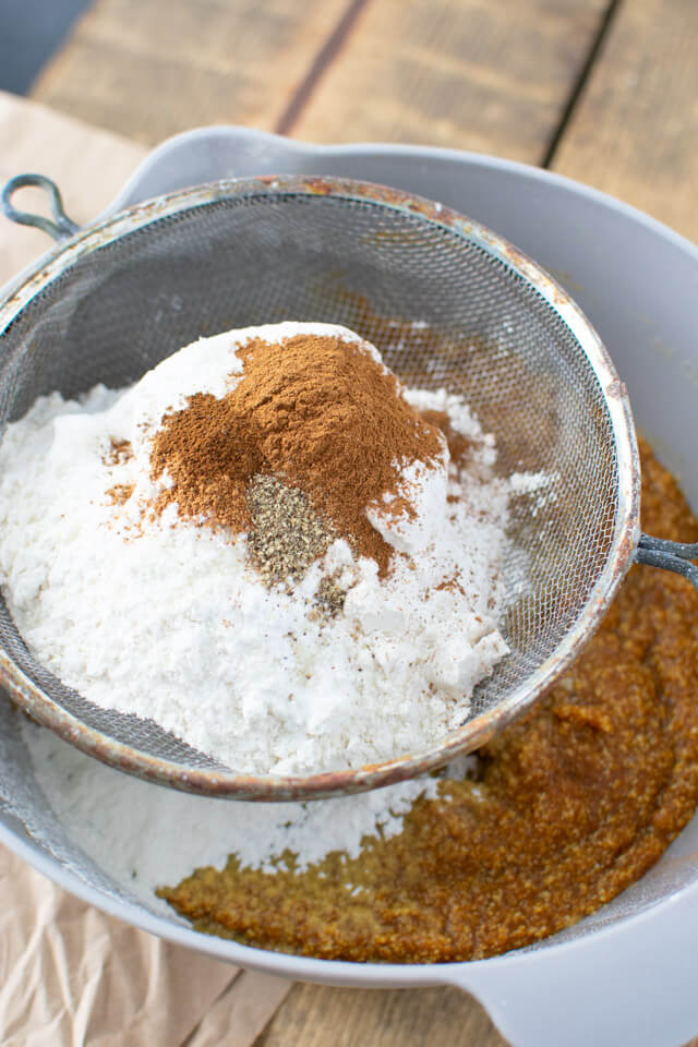 Sifting dry ingredients into pumpkin batter ingredients