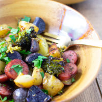Closeup of smoked sausage and potatoes and veggies in a bowl with a fork