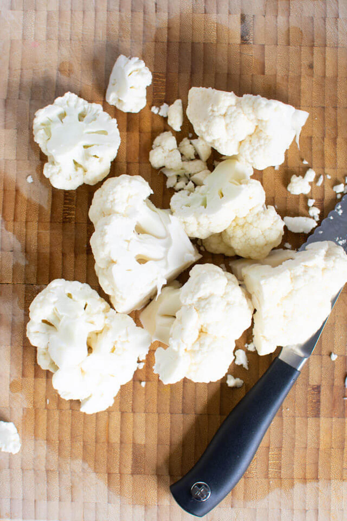 Cauliflower chopped into smaller pieces on cutting board, ready for food processor