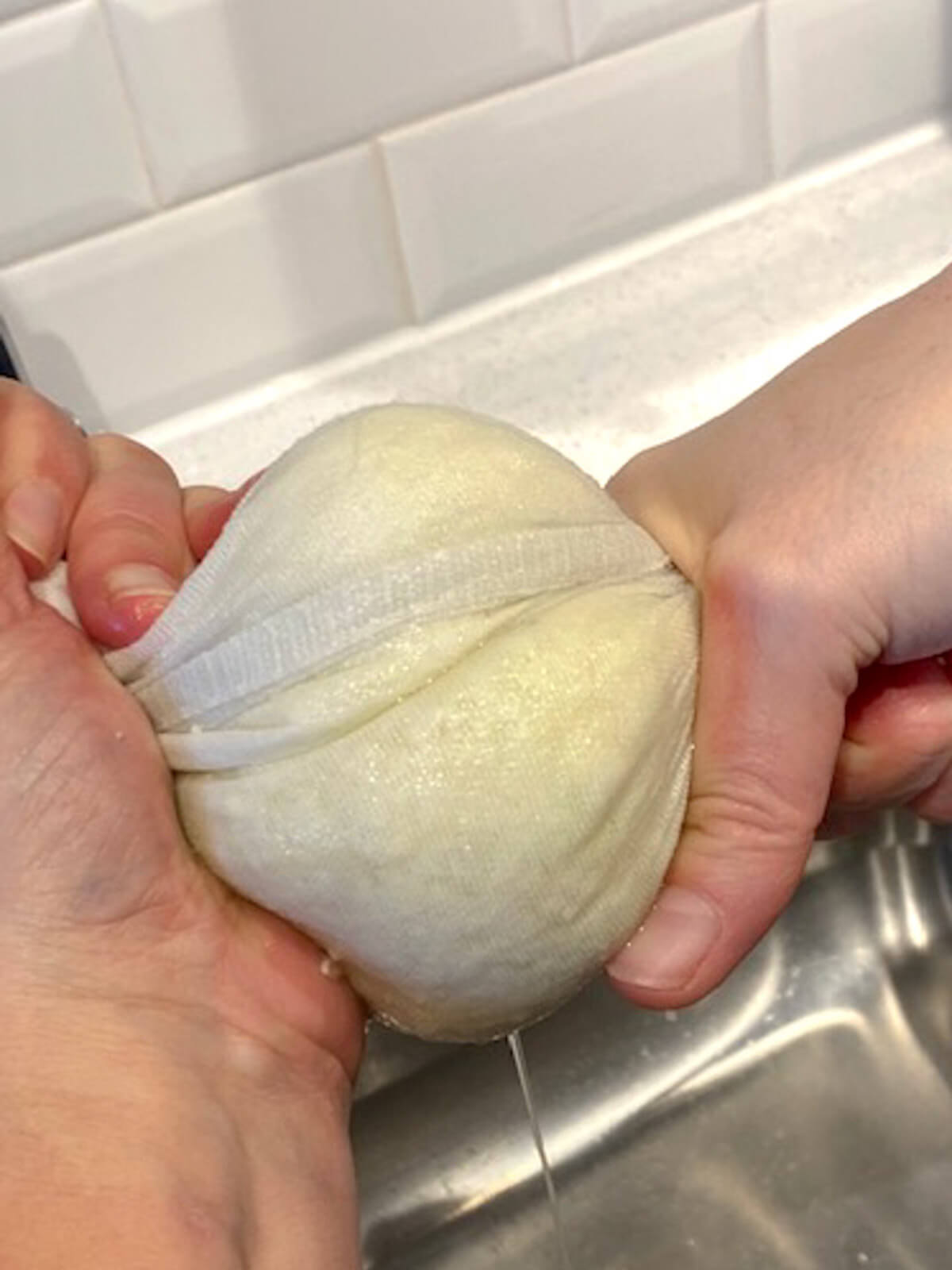 Squeezing water out of the cauliflower rice that's wrapped in a flour sack towel