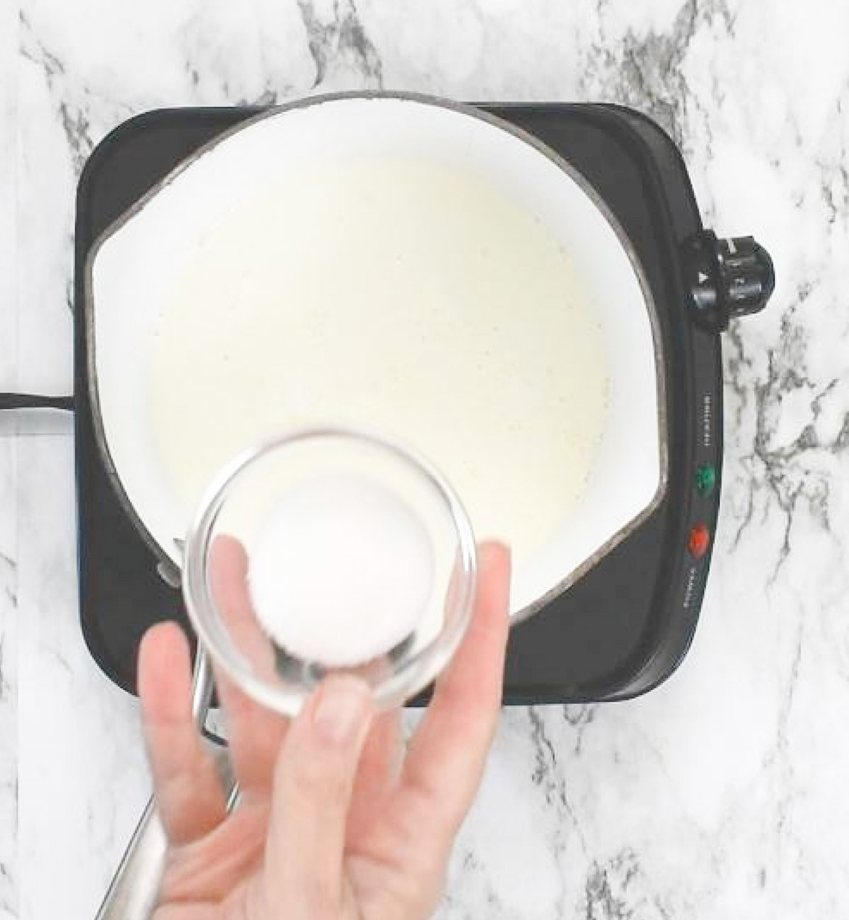 Adding sugar to hot cream in the saucepan