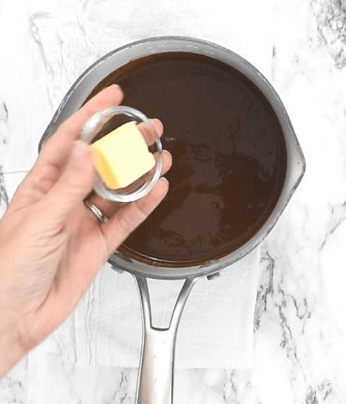Adding butter to chocolate in pan.