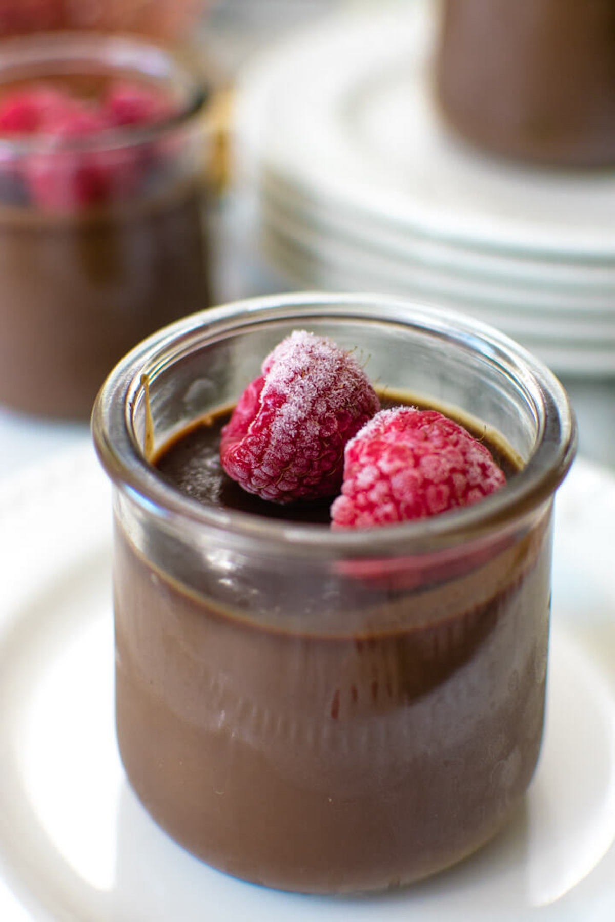 Closeup of a jar of chocolate custard with frozen raspberries on top