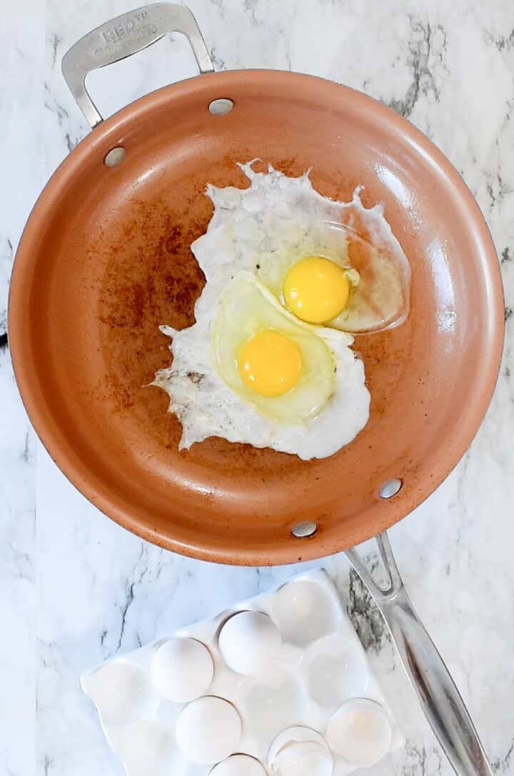 two eggs frying in a skillet