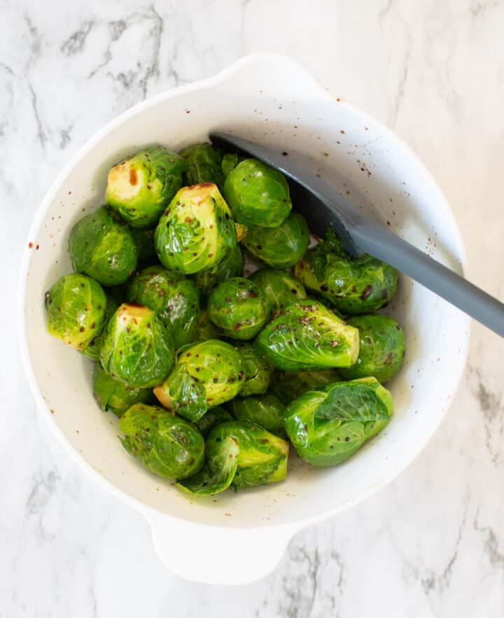 stirring brussels sprouts in bowl with seasonings