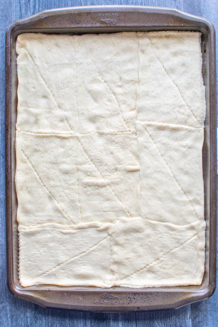 crescent roll dough spread on baking sheet pan