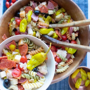 a serving of pasta salad with large bowl of pasta salad in background