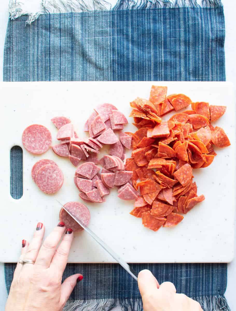 chopping salami and pepperoni on a cutting board