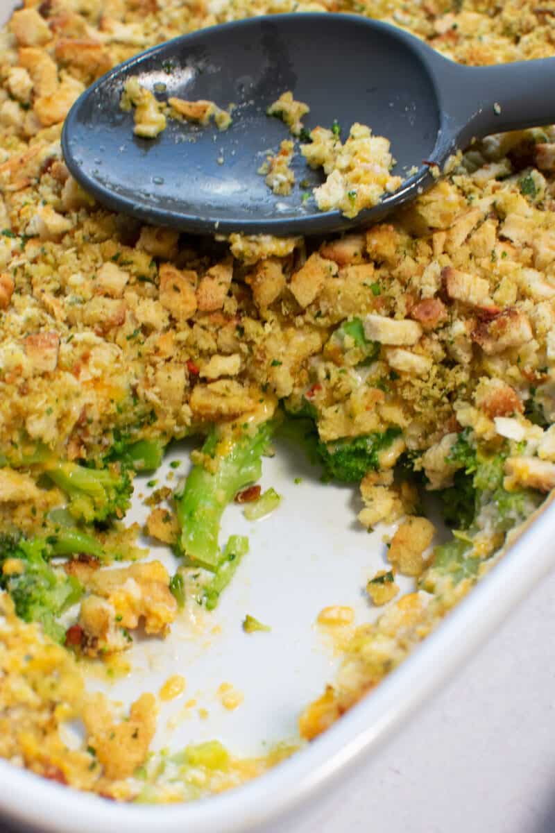 baked cheesy broccoli casserole with a serving scooped out of the baking dish