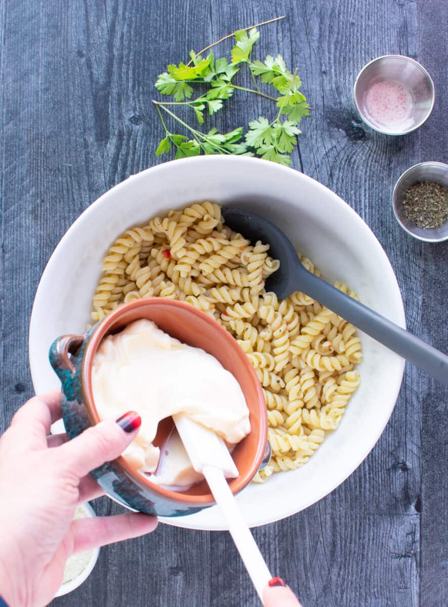 adding mayo to bowl with rotini pasta