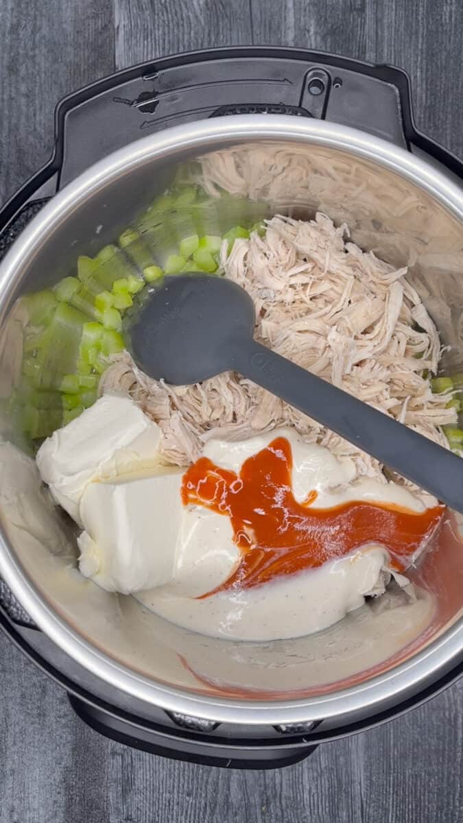 adding shredded chicken, cream cheese, ranch dressing and hot sauce to instant pot