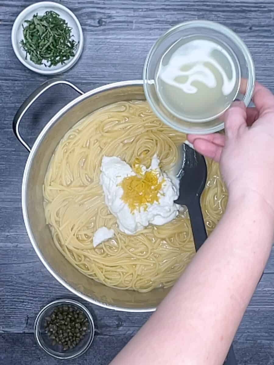 adding lemon zest and lemon juice to pasta in pot