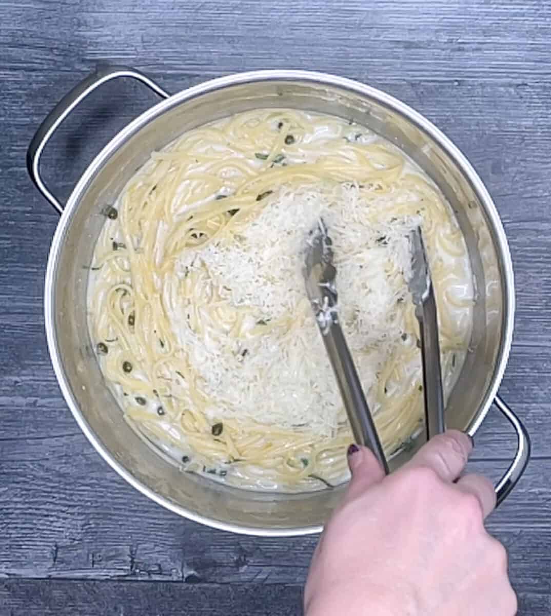 adding parmesan cheese to pasta in pot