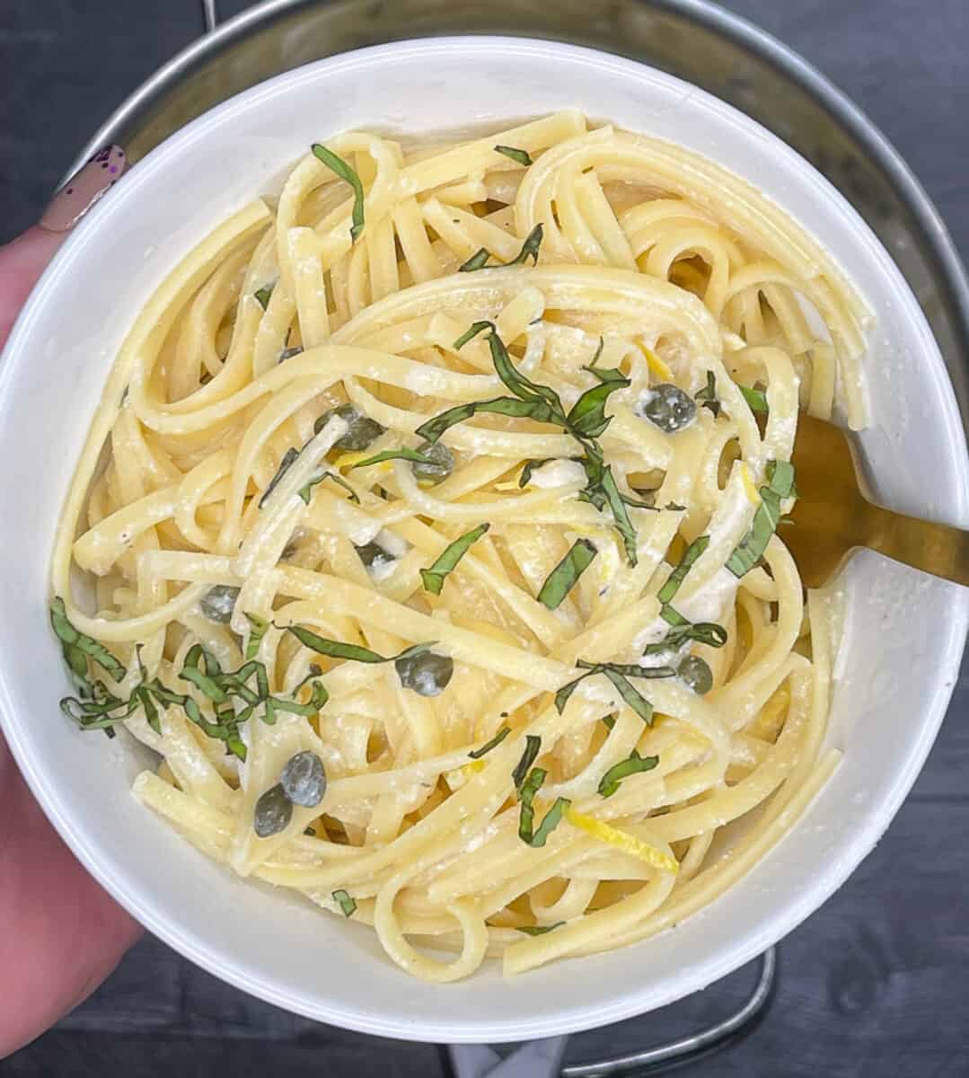 closeup of pasta dish in a bowl topped with fresh basil