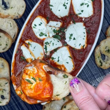 dipping a piece of toasty bread into the goat cheese dip with marinara