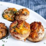 Closeup of stuffed mushrooms on white plate with denim blue napkin in background