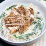 jerk chicken pasta with veggies in a white bowl with a yellow and white striped napkin underneath