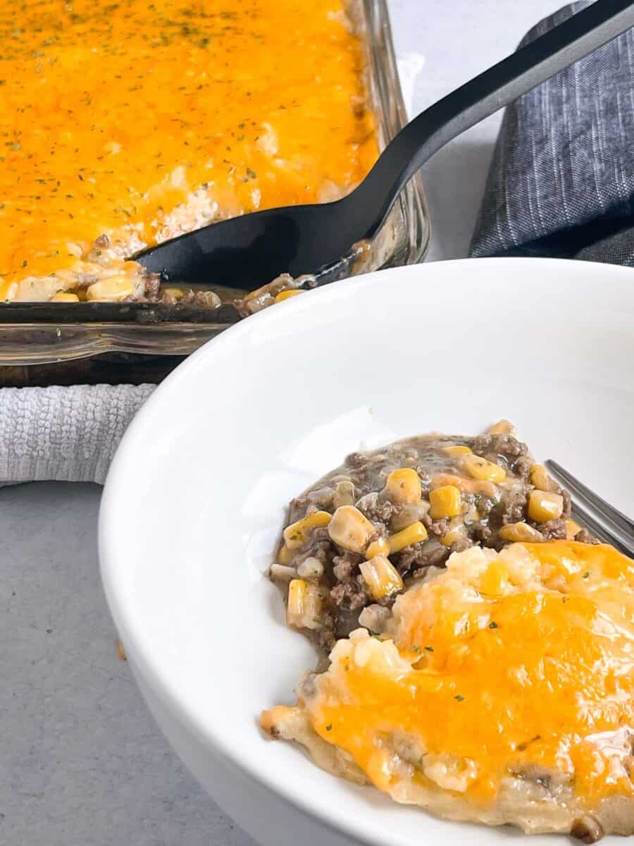 closeup view of cheesy potatoes on top of beef mixture in a white bowl