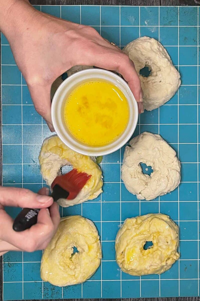 brushing formed bagels with egg wash