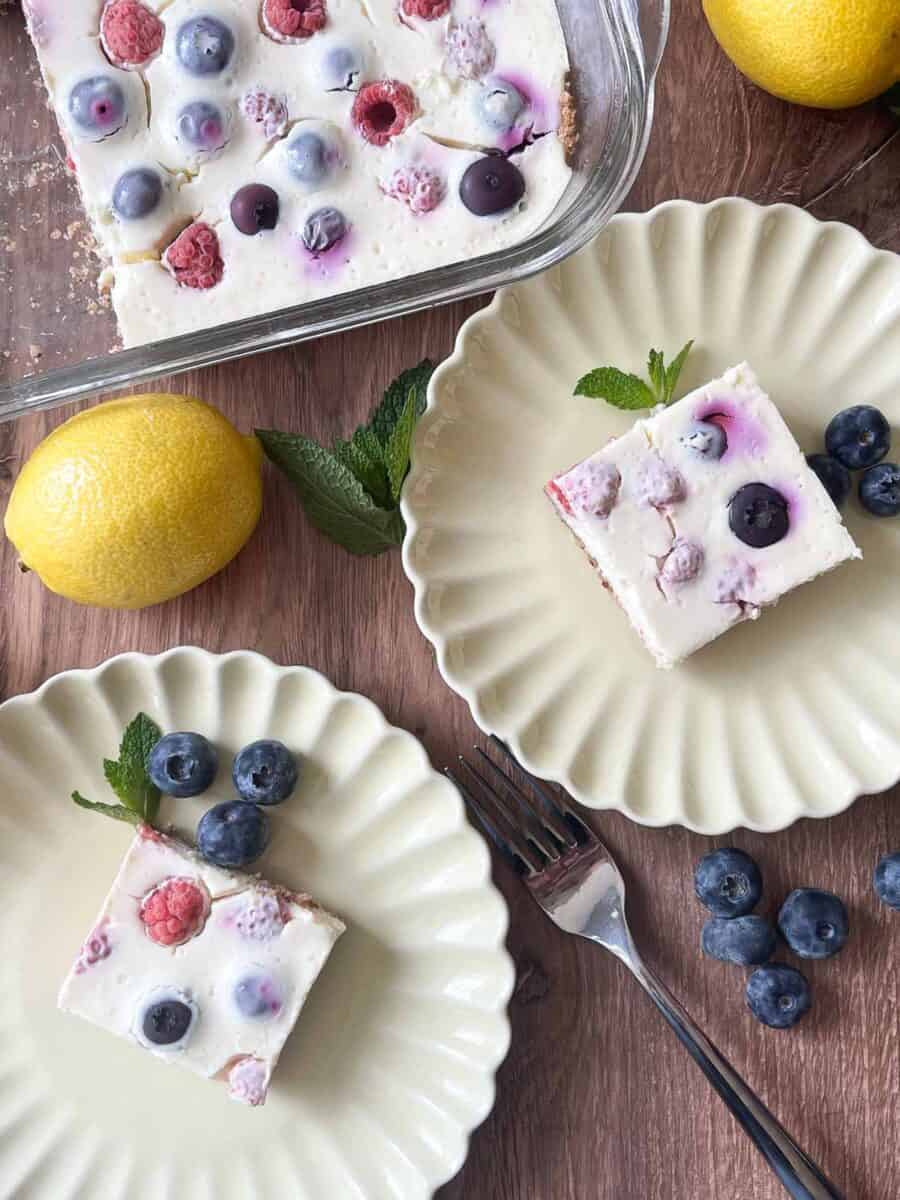 overhead view of two slices of lemon berry cheesecake bars on two plates