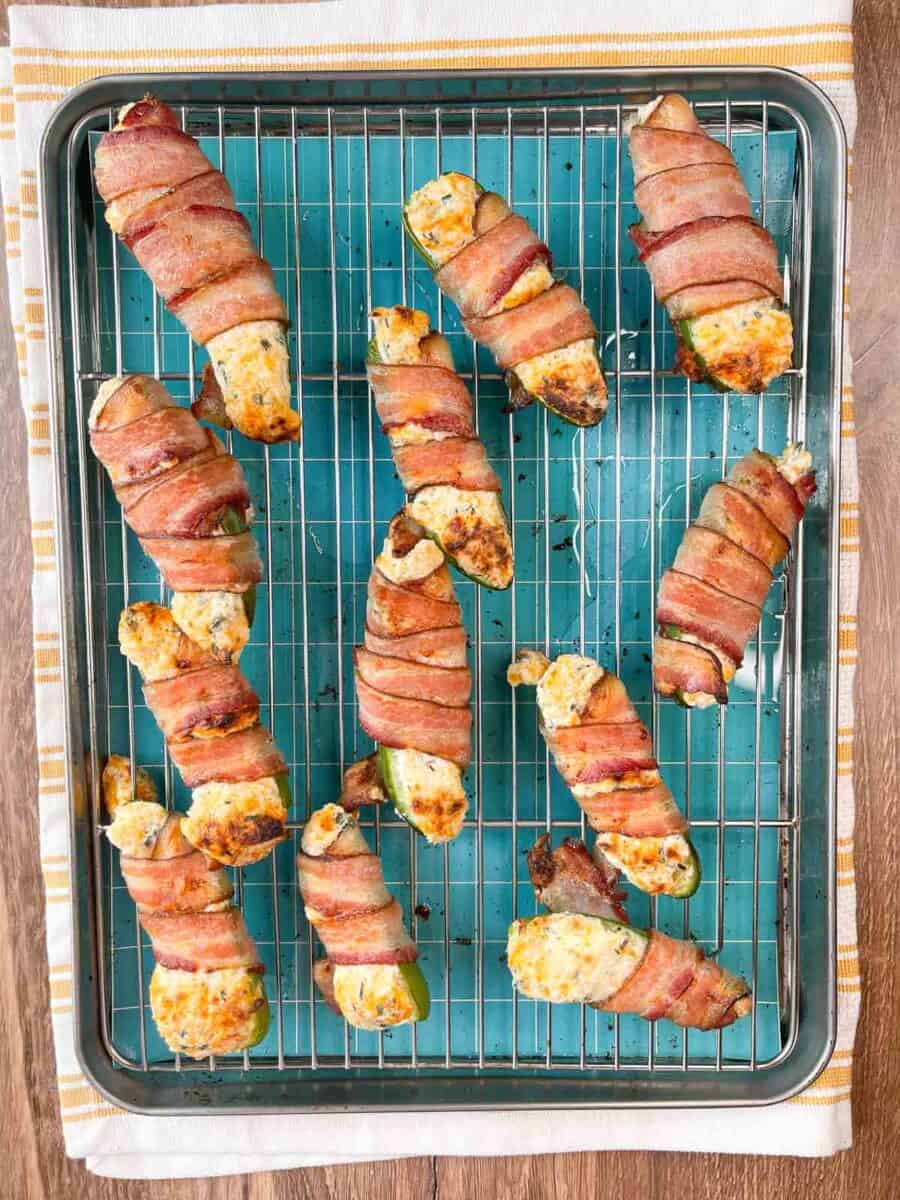 baked bacon wrapped jalapeños overhead view on a baking pan with a metal rack