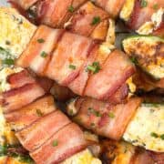 very closeup view of bacon wrapped stuffed cheese jalapeños on a white plate