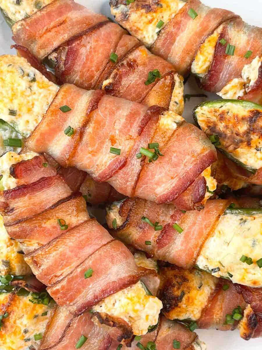 very closeup view of bacon wrapped stuffed cheese jalapeños on a white plate