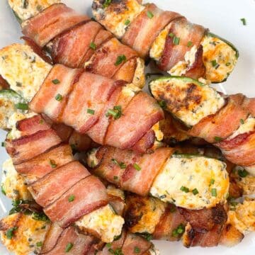 overhead view of cheesy stuffed jalapeรฑos on a white plate