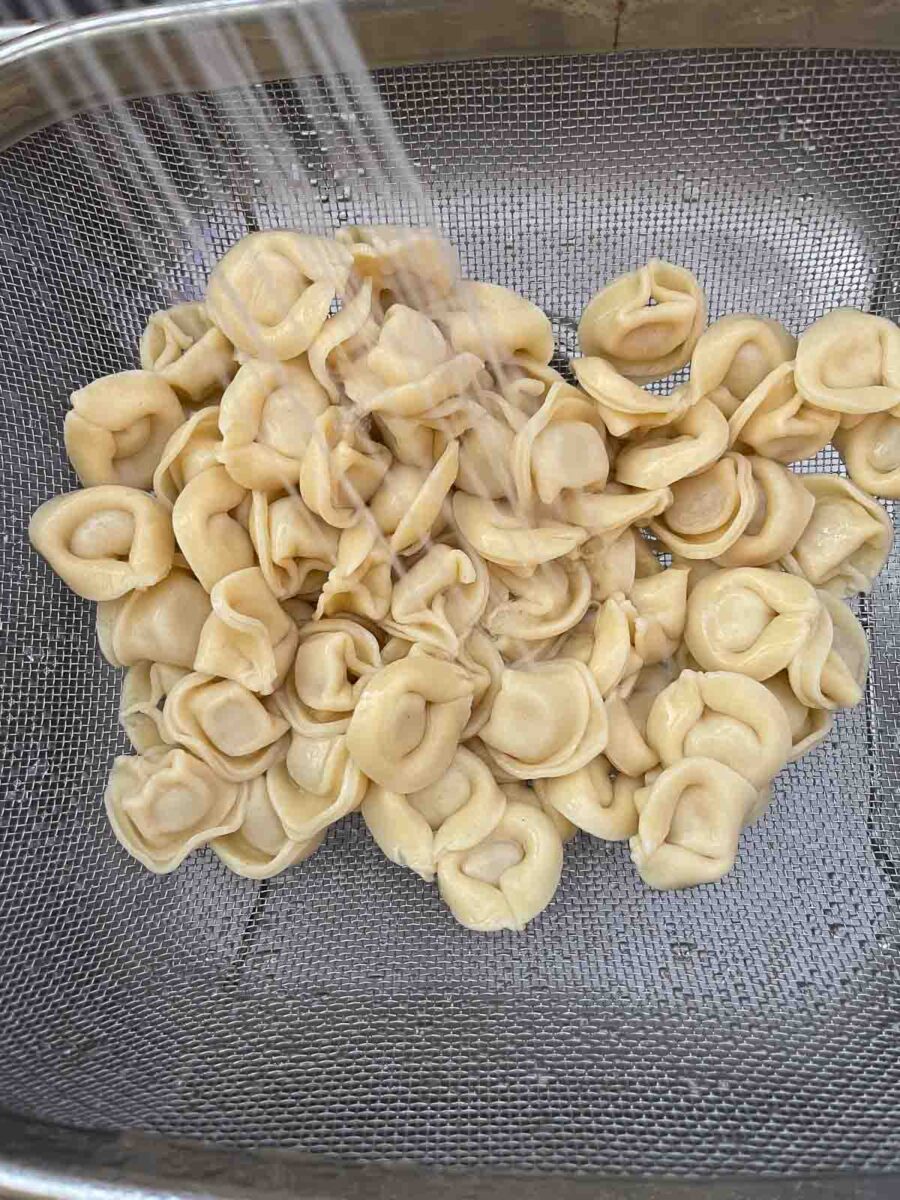 rinsing cheese tortellini in a colander
