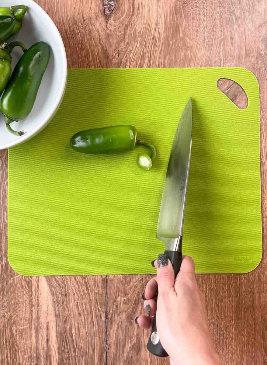 overhead view of cutting the stem part off a whole jalapeño