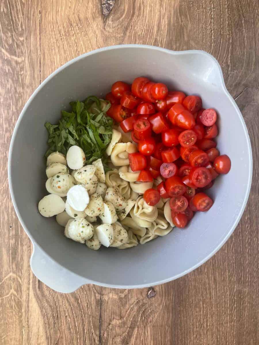 all ingredients for the caprese pasta salad added to a gray mixing bowl