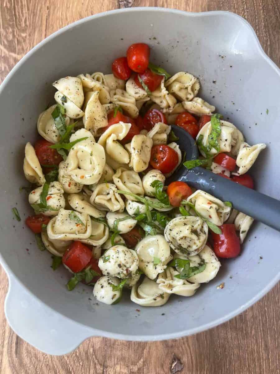 all ingredients for the pasta salad mixed together in a gray mixing bowl