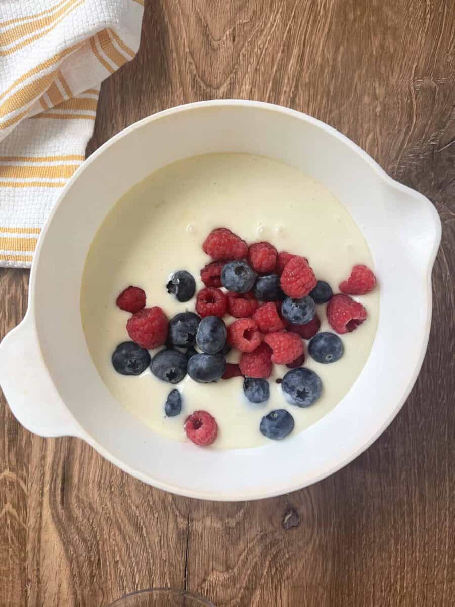 berries added to cheesecake mixture in a bowl