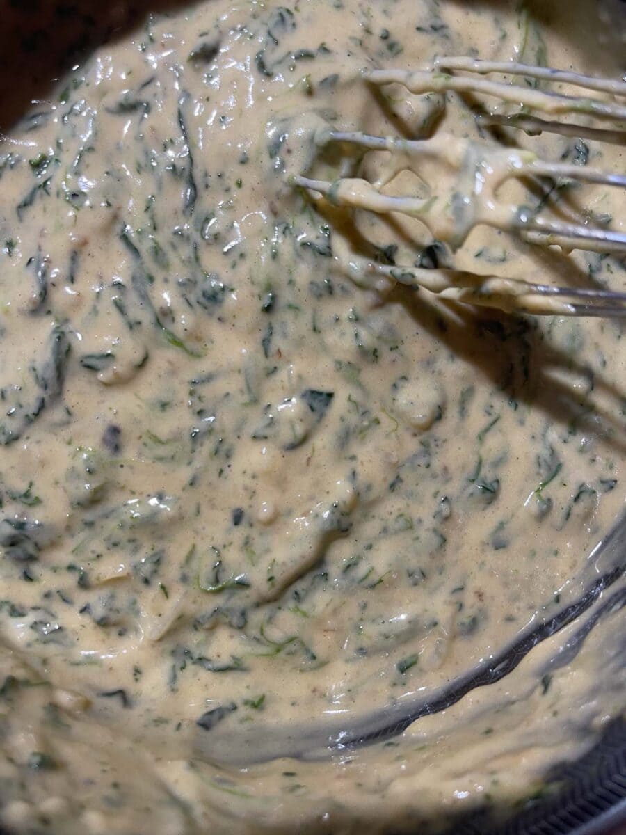 mixing spinach into cheese sauce in pot until all is combined