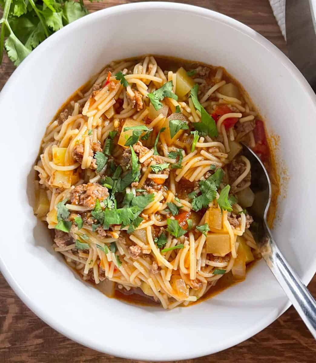 overhead view of cooked fideo with ground beef in a small white bowl