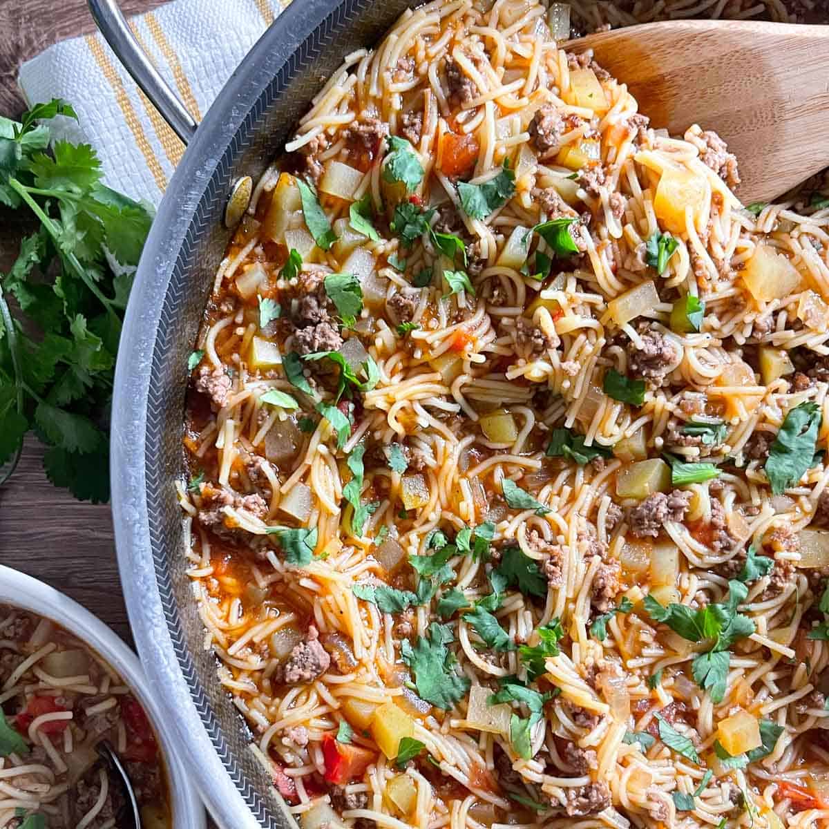 overhead view of finished fideo with ground beef in a skillet sprinkled with parsley