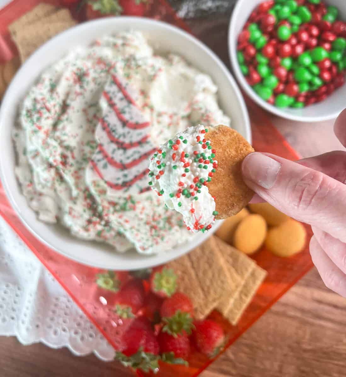 a closeup view of a vanilla wafer cookie with dip on it, a person is holding it close up