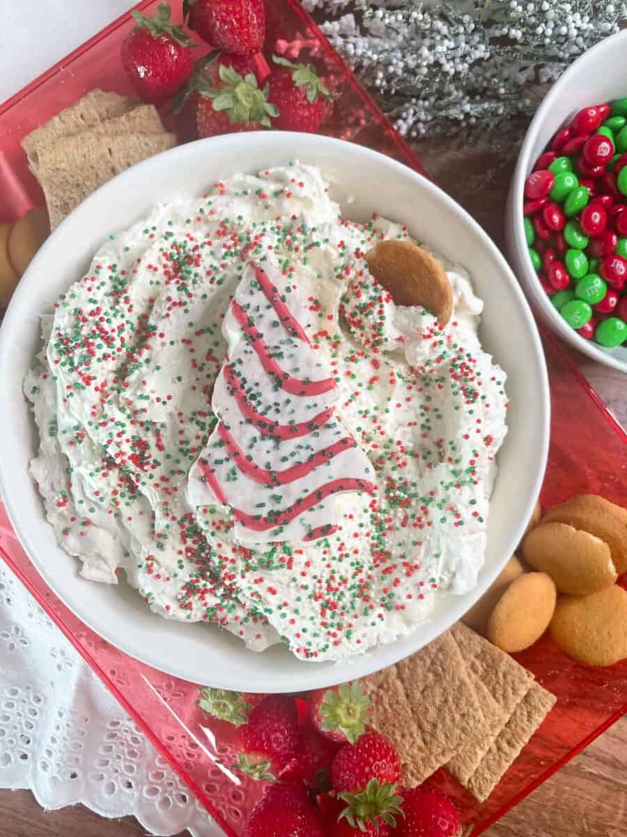 overhead view of Christmas tree cake dip in a bowl with sprinkles on top and a whole christmas tree cake on top of dip