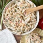 cheddar and sour cream macaroni salad in a white bowl with a wooden serving spoon and on a serving plate